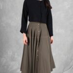 LOUISE flared midi skirt sewing pattern: front view of the olive-khaki skirt with a buttoned waistband, worn with a black top.