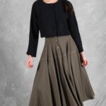 LOUISE circle skirt sewing pattern: model wearing the flowing khaki midi skirt with front buttons and a fitted black blouse.