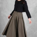LOUISE full skirt sewing pattern: model holding out the hem of a khaki flared midi skirt to show its volume.