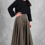 LOUISE button-front skirt sewing pattern: front detail of the khaki flared skirt, gathered-looking panels and a hand on the hip.