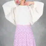 KELIS batwing sleeve top sewing pattern front detail with both arms raised near the face, highlighting the loose cream sleeves and wide cuffs.