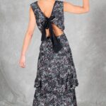FOYS sewing pattern: fOYS open-back dress sewing pattern shown from behind as the model lifts one arm, highlighting the deep V-back and black ribbon bow above the waist.