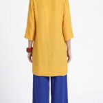 Loose-fit tunic sewing pattern MERVEILLE: back view, loose mustard yellow tunic with three-quarter sleeves over royal blue pants