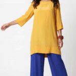 Loose-fit tunic sewing pattern MERVEILLE: front view, mustard yellow tunic worn with royal blue wide pants
