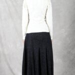 LANGE flared skirt sewing pattern back view: model in a textured dark charcoal midi skirt with wide inverted pleats at the hem, white fitted top and black lace-up boots.