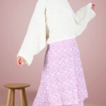 BOHEME maxi skirt sewing pattern shown in a pink-and-lilac printed skirt with overlapping ruffles, worn with a loose white blouse against a pale pink wall.