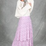 Three-quarter view of the BOHEME maxi skirt sewing pattern in lilac floral fabric, worn with an oversized white blouse and revealing the hip-level ruffle.