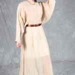 LOVY long dress sewing pattern in cream: relaxed batwing sleeve shown in a standing pose with one arm raised.