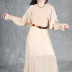 LOVY flowing dress sewing pattern from the front: cream fabric, loose batwing sleeves, defined waist and full-length skirt.