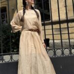 LOVY boho dress sewing pattern worn outdoors: flowing cream maxi dress with batwing sleeves and a cinched waist.