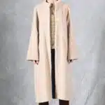 VIVIANE long coat sewing pattern: front view of a beige overcoat with button closure, high collar and raglan sleeves.