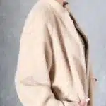 Side view of VIVIANE long beige coat sewing pattern, showing the profile and pockets with the model’s hands inside.