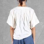 Back view of the CALYS top sewing pattern in lightweight white fabric, showing its gently gathered drape, rounded neckline and broad short sleeves.