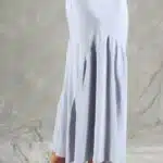 GIULIA sewing pattern: side and back detail of the GIULIA skirt sewing pattern in light blue, showing its smooth line over the hips and flared hem above white sandals.