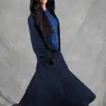 Modelo vistiendo un abrigo largo con capucha, confeccionado con un patrón de abrigo con capucha, que muestra un diseño semiajustado, con vuelo y cierre de botones.