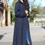 Modelo vistiendo un abrigo largo con capucha, confeccionado con un patrón de abrigo con capucha, que muestra un diseño semiajustado, con vuelo y cierre de botones.