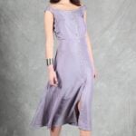 A woman with long dark hair poses in a lilac sleeveless dress crafted with a summer dress pattern, adorned with buttons down the front.