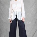 A woman is wearing a sheer white shirt with floral embroidery, crafted with a shirt sewing pattern.