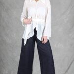 A woman is wearing a sheer white shirt with floral embroidery, crafted with a shirt sewing pattern.