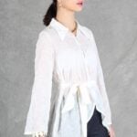 A woman is wearing a sheer white shirt with floral embroidery, crafted with a shirt sewing pattern.