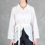 A woman is wearing a sheer white shirt with floral embroidery, crafted with a shirt sewing pattern.
