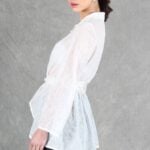 A woman is wearing a sheer white shirt with floral embroidery, crafted with a shirt sewing pattern.