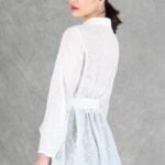 A woman is wearing a sheer white shirt with floral embroidery, crafted with a shirt sewing pattern.