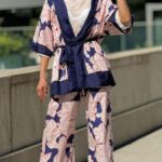 A woman stands outdoors wearing sunglasses and a fashionable outfit consisting of a white lace top, wide-leg pants, and a stunning kimono jacket made with a kimono jacket pattern.