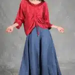 MAR women’s ruched top sewing pattern: front view of the red gathered blouse worn with a long blue skirt.