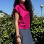 Model wearing a bright pink draped top, showcasing the elegant fit of the sewing pattern, paired with a denim skirt.