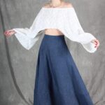 Model wearing a flowy summer top made from a summer top sewing pattern and a long skirt, . The top is an off-the-shoulder white lace design, paired with a blue maxi skirt.