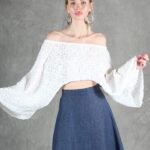 Model wearing a flowy summer top made from a summer top sewing pattern and a long skirt, . The top is an off-the-shoulder white lace design, paired with a blue maxi skirt.