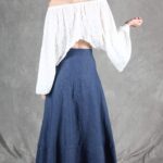 Model wearing a flowy summer top made from a summer top sewing pattern and a long skirt, . The top is an off-the-shoulder white lace design, paired with a blue maxi skirt.