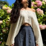 Model wearing a flowy summer top made from a summer top sewing pattern and a long skirt, . The top is an off-the-shoulder white lace design, paired with a blue maxi skirt.
