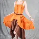 Model wearing a flowing top and skirt with an asymmetrical hem, made from a top and skirt sewing pattern. The orange top drapes elegantly over a brown skirt with a satin finish, creating a layered effect.