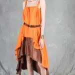Model wearing a flowing top and skirt with an asymmetrical hem, made from a top and skirt sewing pattern. The orange top drapes elegantly over a brown skirt with a satin finish, creating a layered effect.
