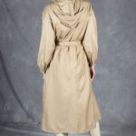 Back view of the BLIZZARD raincoat sewing pattern, showing the beige coat’s hood, gathered waist beneath the belt and long hem.