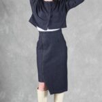 "Model wearing a denim jacket crafted with a cropped jacket pattern, featuring a minimalist design with a round neckline, long sleeves, and two blue buttons, paired with a high-waisted skirt.
