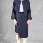 "Model wearing a denim jacket crafted with a cropped jacket pattern, featuring a minimalist design with a round neckline, long sleeves, and two blue buttons, paired with a high-waisted skirt.
