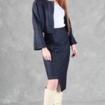 "Model wearing a denim jacket crafted with a cropped jacket pattern, featuring a minimalist design with a round neckline, long sleeves, and two blue buttons, paired with a high-waisted skirt.