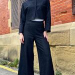 "Model wearing a denim jacket crafted with a cropped jacket pattern, featuring a minimalist design with a round neckline, long sleeves, and two blue buttons, paired with a high-waisted skirt.