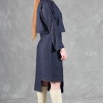 Side view of the JANYS asymmetrical pencil skirt sewing pattern, showing its fitted silhouette and longer back hem with cream boots.