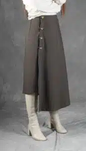 Model wearing an elegant wrap skirt crafted with a wrap skirt pattern, featuring a side button closure and a chic, flowing silhouette, paired with a light blouse and knee-high boots.