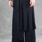 Detail of the LE SILENCE DU VENT pants sewing pattern: black asymmetrical skirt overlay draping over wide trouser legs.