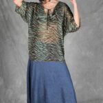 A model wearing the relaxed SOL tunic sewing pattern as part of an everyday outfit. The V-shaped neckline, generously cut body and seamless-looking Japanese sleeves give the top its airy drape.