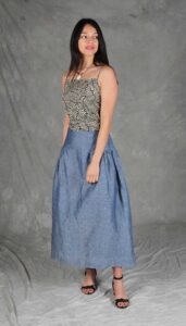 Model wearing a skirt sewn from the Noa gathered skirt sewing pattern, made in blue chambray fabric, featuring a wide yoke waistband and soft gathers, perfect for confident beginners and everyday wear.