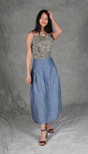Modelo luciendo una falda confeccionada con el Patrón de Falda Fruncida para Principiantes "Noa", en tela de chambray azul. La prenda destaca por su canesú ancho, frunces sutiles y silueta evasé, ideal para costureras principiantes.