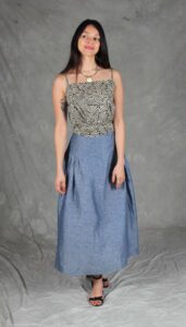 Model wearing a skirt sewn from the Noa gathered skirt sewing pattern, made in blue chambray fabric, featuring a wide yoke waistband and soft gathers, perfect for confident beginners and everyday wear.