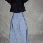 Model wearing a skirt sewn from the Noa gathered skirt sewing pattern, made in blue chambray fabric, featuring a wide yoke waistband and soft gathers, perfect for confident beginners and everyday wear.