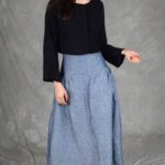Model wearing a skirt sewn from the Noa gathered skirt sewing pattern, made in blue chambray fabric, featuring a wide yoke waistband and soft gathers, perfect for confident beginners and everyday wear.